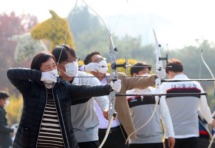 Citizens wearing masks try archery lessons in Daegu, 300 kilometers southeast of Seoul, on Nov. 17, 2020, in an event held to ease pandemic fatigue. (Yonhap)