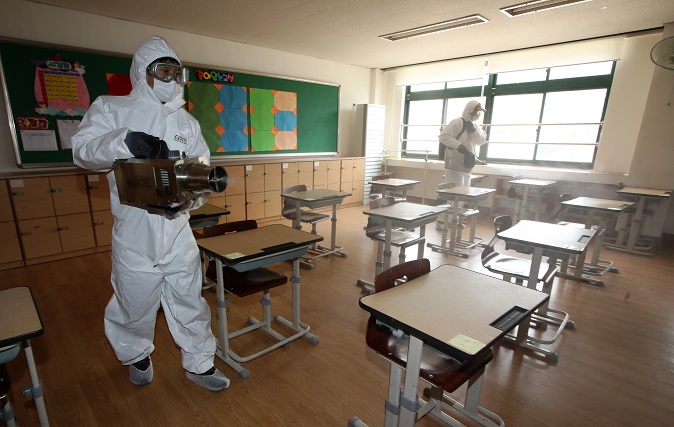 This file photo, taken Feb. 24, 2021, shows quarantine officials disinfecting a classroom at an elementary school in Gwangju, 329 kilometers south of Seoul, to prevent the spread of COVID-19 cases. (Yonhap)