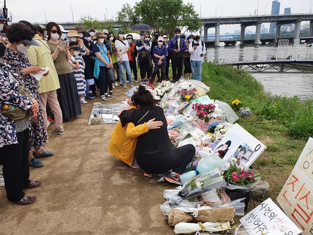 Two people embrace as they weep in Banpo Han River Park in Seoul on May 23, 2021, over the death of Son Jeong-min, a 22-year-old medical school student, near the spot where he was last seen. (Yonhap)