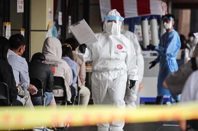 A health worker in a protective suit guides citizens at a makeshift virus testing clinic in Seoul on May 29, 2021. (Yonhap)