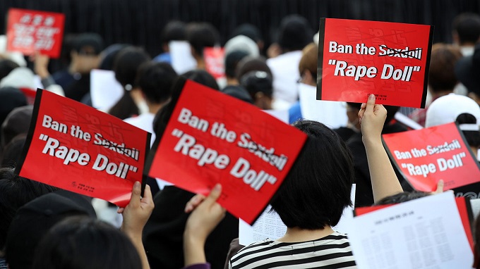 The undated file photo shows protestors holding signs that read, "Outright Ban on Rape Dolls."