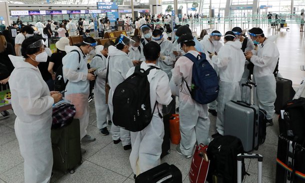 Travelers, clad in hazmat suits and face shields, prepare to check in for outbound flights at Incheon International Airport, west of Seoul, on June 24, 2021. (Yonhap)