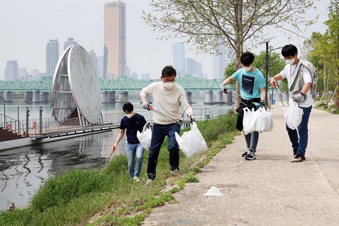 SK Innovation Co. employees pick up trash at a Han River park in Seoul in this photo provided by the company.