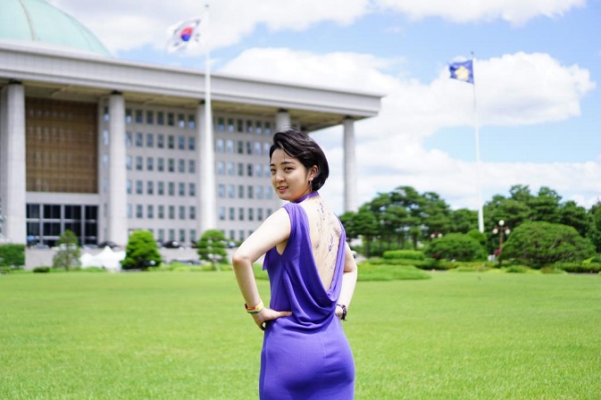 Rep. Ryu Ho-jeong of the progressive minor Justice Party poses in the National Assembly complex in Seoul in a purple dress, showing erasable tattoos on her back, in this photo provided by her office on June 16, 2021.