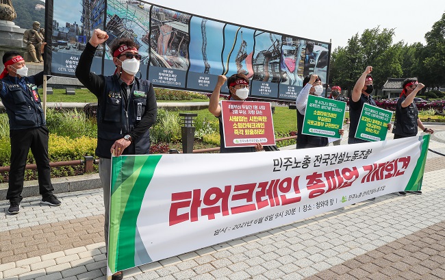 Korean Construction Workers Union tower crane operators shout slogans to announce their general strike during a press conference outside Cheong Wa Dae in Seoul on June 8, 2021.  (Yonhap)