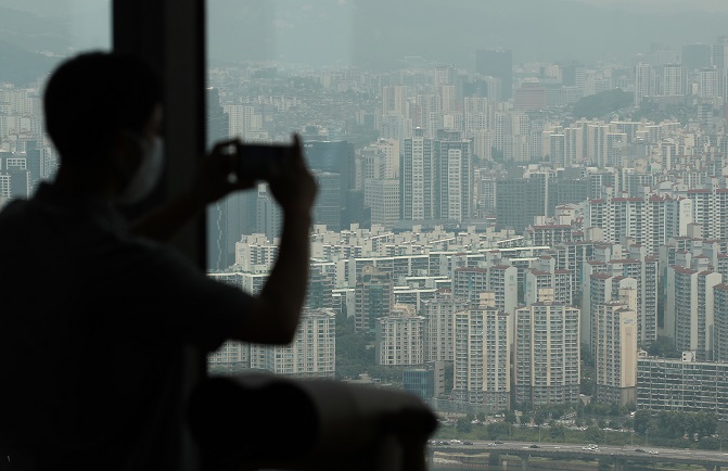 A person takes a photo of apartment buildings in downtown Seoul from a skyscraper on June 13, 2021. (Yonhap)