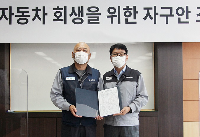 SsangYong Motor Co.'s labor union chief Jung Il-kwon (L) and court-appointed manager Chung Yong-won pose for a photo after signing an agreement on self-help measures for the financially troubled automaker at its Pyeongtaek factory, 70 kilometers south of Seoul, on June 14, 2021, in this photo provided by SsangYong.