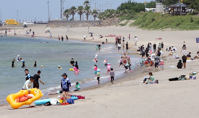 Beachgoers enjoy warm weather on the southern resort island of Jeju on June 27, 2021. (Yonhap)