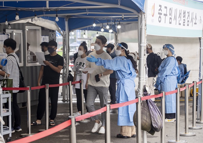 People stand in line to take coronavirus tests at a screening clinic in front of Seoul Station on June 30, 2021. South Korea's daily new virus cases spiked to an over two-month high as a series of cluster infections were reported in the wider Seoul area amid jitters over growing COVID-19 variant cases. (Yonhap)