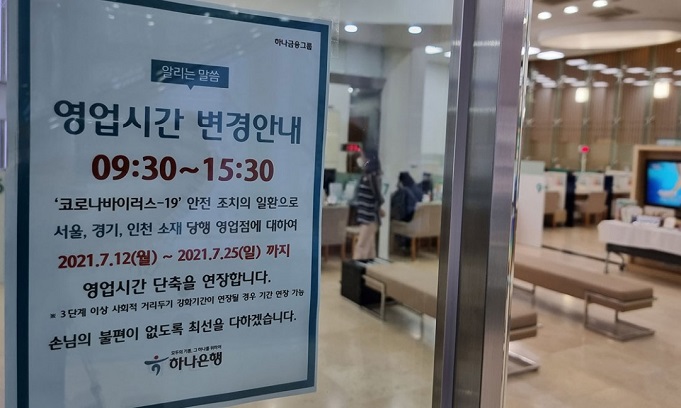 A notice informs people that business hours will be reduced by one hour at a bank in Seoul on July 9, 2021. The measure is part of steps to be taken under Level 4 of social distancing that will be introduced on July 12 amid concerns of a fourth wave of COVID-19. (Yonhap)