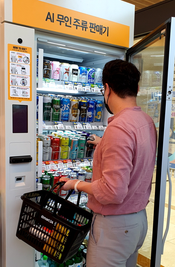 This photo provided by E-Mart24 Inc. on July 29, 2021, shows a customer selecting beer from a self-serve machine in Seoul.