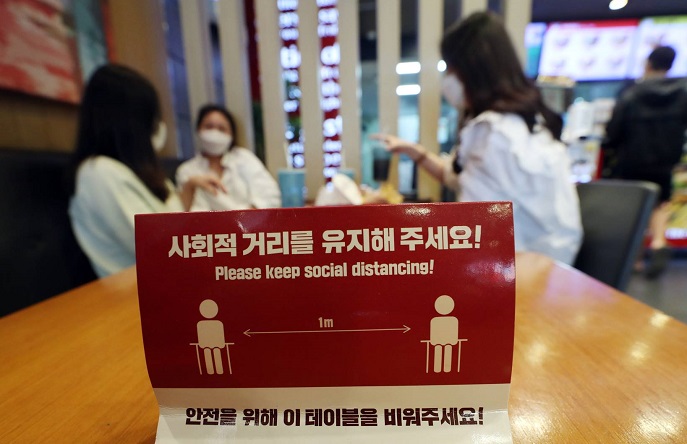 This photo from Yonhap News TV shows social distancing rule guidance and customers at a cafe in Seoul.
