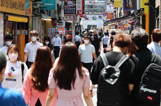 This file photo from June 21, 2021, shows people walking on the streets of Myeongdong in central Seoul. (Yonhap)