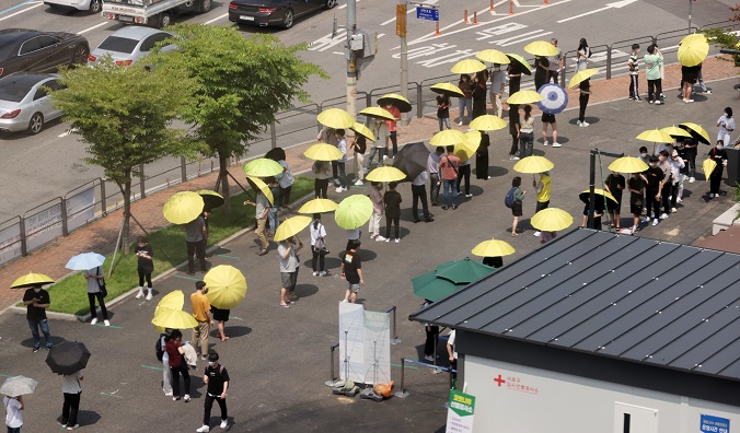 Citizens wait in line with umbrellas for COVID-19 tests in southern Seoul on July 2, 2021. (Yonhap)