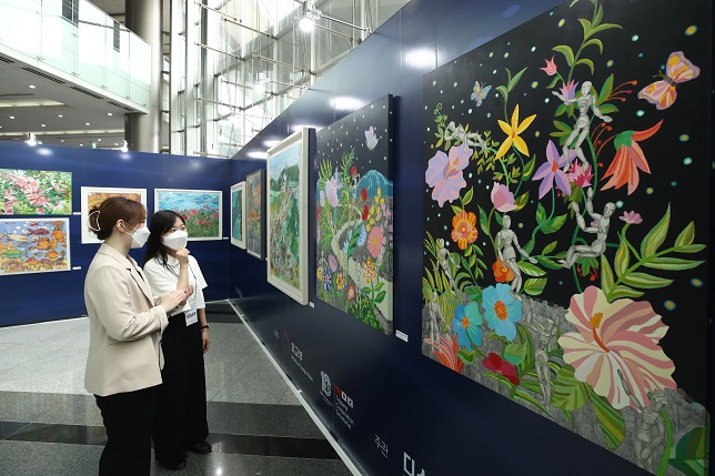 Visitors look at artworks on display during an exhibition by 13 artists of South Korea, China and Japan with developmental disorders at the COEX convention center in Seoul on July 8, 2021. (Yonhap)