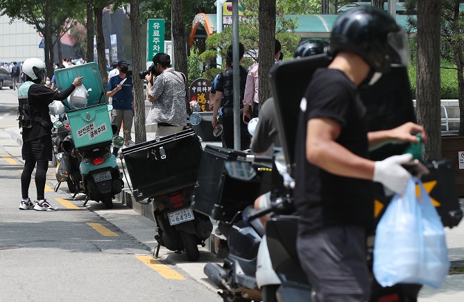 Delivery workers carry takeout meals in central Seoul on July 12, 2021. (Yonhap)