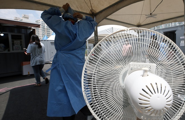 A medical worker stands next to a fan at a clinic in Gangneung, 237 kilometers east of Seoul, on July 16, 2021, amid the scorching summer heat. (Yonhap)