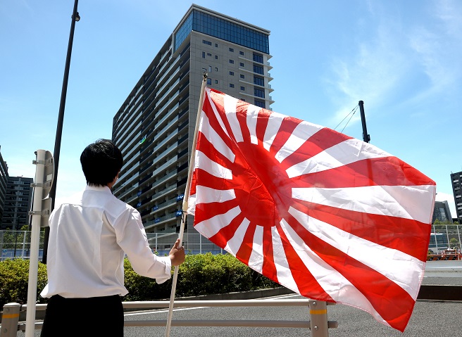 A member of the far-right National Party of Japan waves the Rising Sun Flag outside the Olympic athletes' village in Tokyo on July 16, 2021, in protest to a message hung outside South Korean athletes' rooms that some Japanese accuse of being overly political and anti-Japanese. (Yonhap)