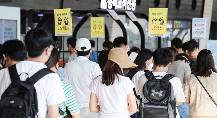 Travelers wait in line, with social distancing signs displayed in the background, at Gimpo International Airport in Seoul on July 30, 2021. (Yonhap)