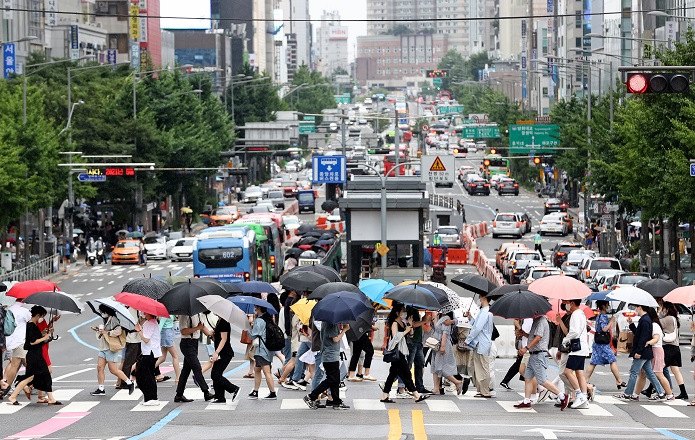 This file photo, taken July 3, 2021, shows people crossing a street near Hongik University in Seoul. (Yonhap)