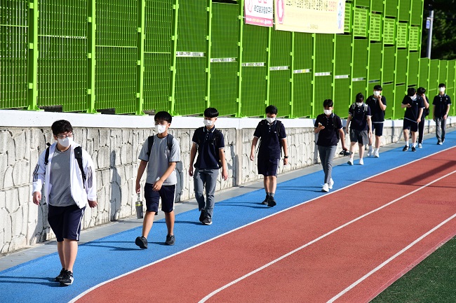 This photo provided by the education office in Jeju, an island off the southern coast of South Korea, shows middle school students on their way to school while social distancing on Aug. 2, 2021.