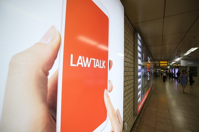 In this file photo, people pass by a billboard advertising LawTalk, an online service that connects clients and lawyers, in Seoul on Aug. 4, 2021. (Yonhap)