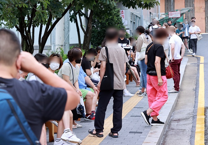 This undated file photo shows foreign workers in line to get tested for COVID-19 in Seoul. (Yonhap)