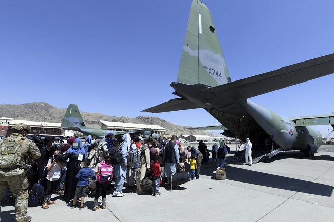 A group of Afghans, who aided South Korea's efforts to help rebuild the war-torn Afghanistan, and their family members board a cargo plane operated by the South Korean air force at an airport in Kabul following the return to power of the Taliban, an Islamic militant group, in this undated photo released by the South Korean foreign ministry on Aug. 25, 2021.