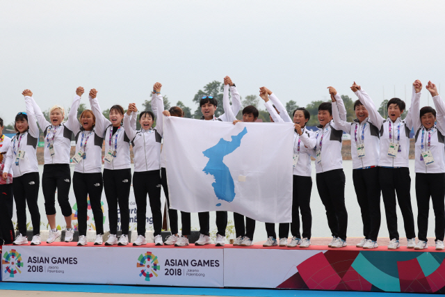 In this file photo from Aug. 26, 2018, members of the unified Korean women's dragon boat racing team stand on the podium during the medal ceremony after winning gold in the women's 500-meter race at the 18th Asian Games in Palembang, Indonesia. (Yonhap)