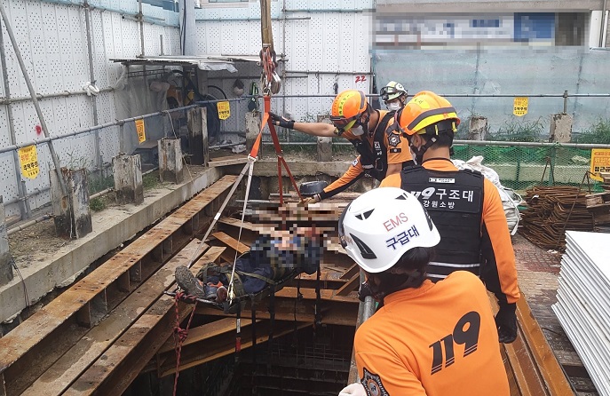 This file photo provided by the Gangwon Fire Headquarters on Aug. 14, 2021, shows emergency responders rescuing a fallen worker at a construction site in Sokcho, Gangwon Province.