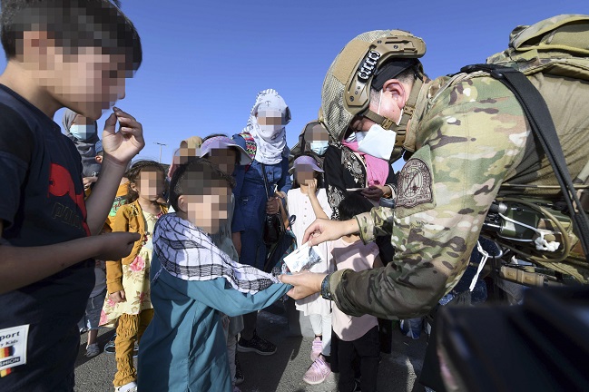 A South Korean soldier of an Air Force's special forces unit gives out snacks to Afghan children, before they and their parents are flown out of Kabul on a military plane in an evacuation operation to bring a total of 391 Afghans who worked for the South and their families to Seoul, in this photo provided by the Air Force on Aug. 26, 2021.