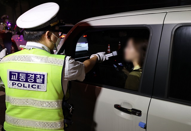 A police officer conducts a roadside breath test, using a newly-developed breathalyzer in Seoul on Sept. 2, 2021. (Yonhap)