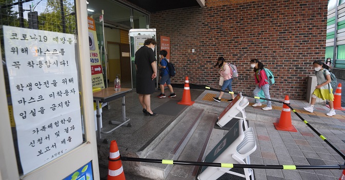 Students enter an elementary school in northern Seoul on Sept. 6, 2021, under a revised distancing measure that eased the attendance cap for in-person classes. (Yonhap)