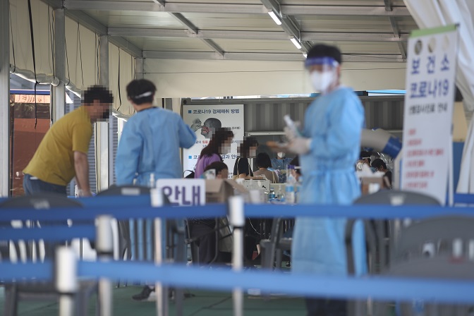 Health workers clad in protective suits guide citizens at a makeshift COVID-19 testing clinic in Seoul on Sept. 12, 2021. (Yonhap)