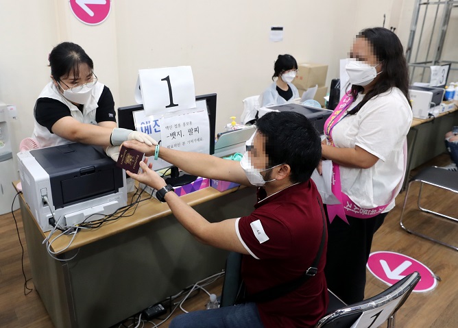 In this file photo, a foreigner receives a bracelet that shows his vaccination status after receiving a COVID-19 vaccine shot at a medical clinic in Busan, about 450 kilometers southeast of Seoul, on Sept. 14, 2021. (Yonhap)