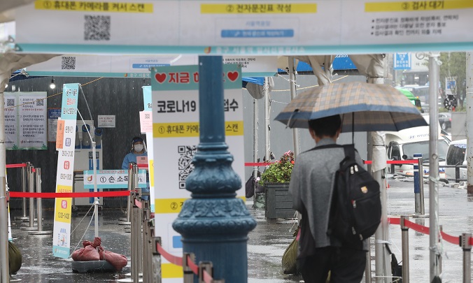 A person waits to take a virus test while holding an umbrella at a screening center in Seoul Station, downtown Seoul, on Sept. 29, 2021. (Yonhap)