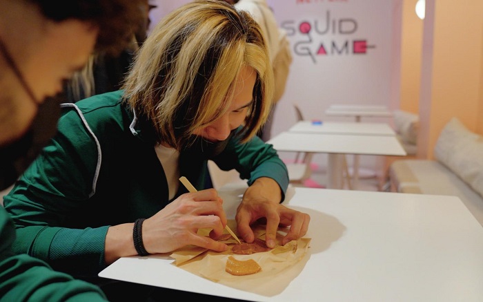 This photo, provided by Netflix France, shows visitors at a pop-up store for the Netflix series "Squid Game" in Paris playing a game of "dalgona bbobggi" on Oct. 3, 2021. 