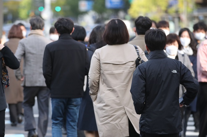 People walk in central Seoul on Oct. 18, 2021, as unseasonably cold weather continued in the morning. (Yonhap)