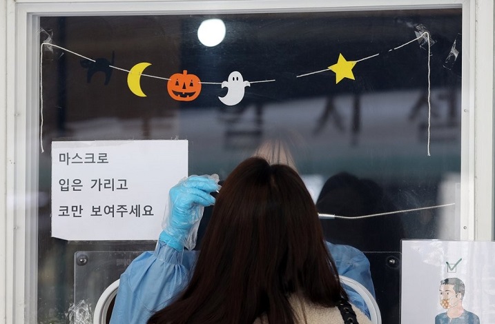 A medical worker takes a sample from a woman at a COVID-19 testing station with Halloween decorations in Seoul on Oct. 26, 2021. (Yonhap)