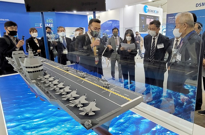 Visitors look at a model of a Korean-style light aircraft carrier of Daewoo Shipbuilding & Marine Engineering Co. during the International Marine, Shipbuilding, Offshore, Oil and Gas Exhibition 2021 at the BEXCO convention center in the southeastern port city of Busan on Oct. 19, 2021. (Yonhap)