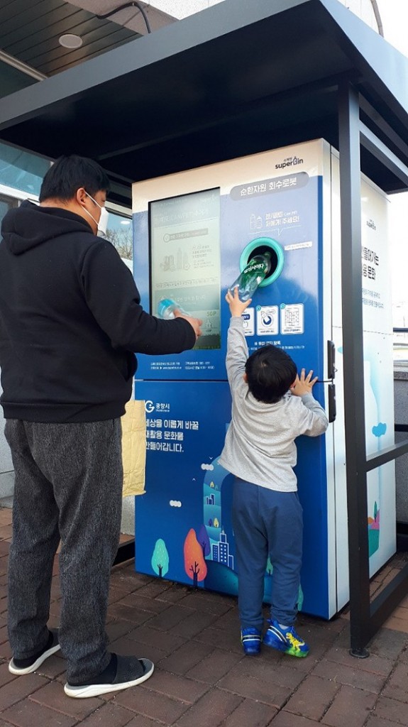 A local resident and his kid puts plastic bottles in Superbin's reverse vending machine in Gwangyang, South Jeolla Province in this photo provided by the city government.