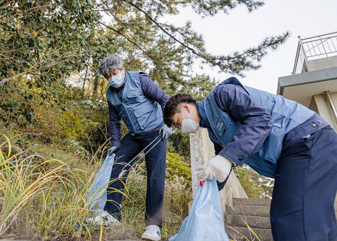 This photo provided by POSCO Engineering & Construction Co. shows volunteer workers picking up trash near the Yongho branch school of Hansan Elementary School in the southern port city of Tongyeong.