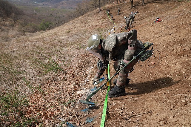 This undated photo, provided by the defense ministry on April 24, 2020, shows soldiers detecting mines at Hwasalmeori (arrowhead) Hill in the South Korean border town of Cheorwon next to the Demilitarized Zone bisecting the two Koreas, prior to the start of the excavation of the remains of soldiers killed in action there during the 1950-53 Korean War. This year's excavation work kicked off on April 20.
