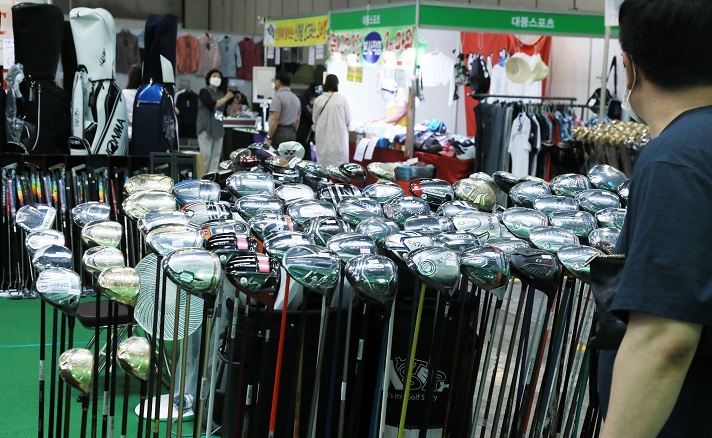 This file photo, taken June 10, 2021, shows people looking at golf clubs and other related equipment at a sales event in Goyang, just north of Seoul. (Yonhap)