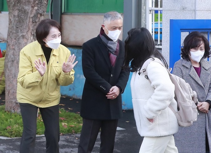Education Minister Yoo Eun-hye (L) greets a student arriving at an elementary school in Seoul on Nov. 22, 2021, as in-person school classes at all kindergartens, elementary, middle and high schools across the country resumed the same day for the first time since the coronavirus pandemic broke out nearly two years ago. (Pool photo) (Yonhap)