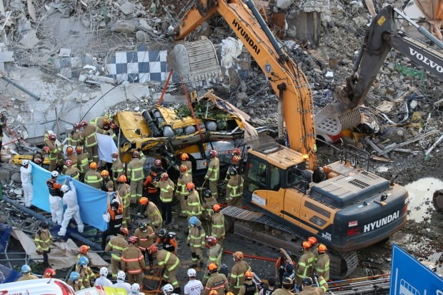 This photo taken on April 4, 2021, shows firefighters rescuing workers buried in the wreckage of a wooden building during the reinforcement work in Gwangju, 330 kilometers south of Seoul. (Yonhap)