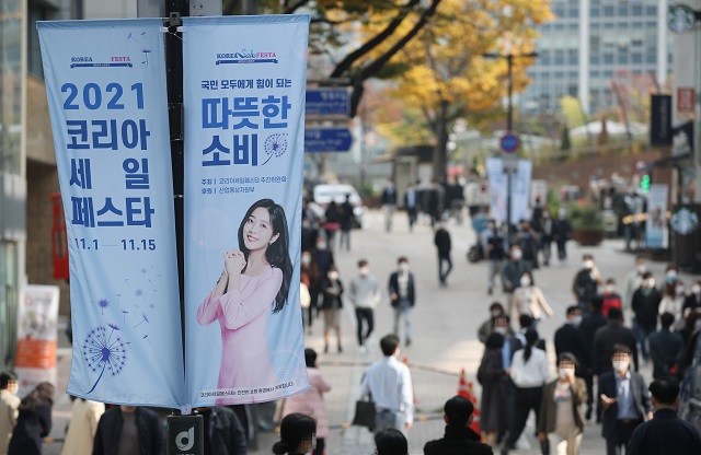 People walk past signs promoting the 2021 Korea Sale FESTA, in the shopping district of Myeongdong in Seoul on Nov. 1, 2021, the first day of the 15-day event to attract foreign tourists and boost domestic consumption. (Yonhap)