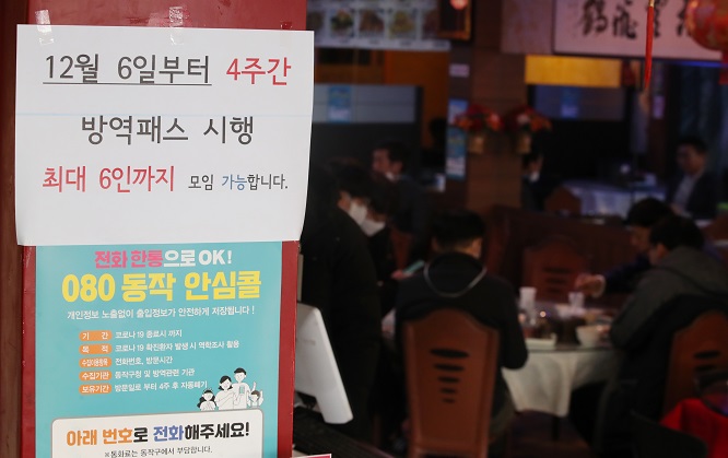 A notice posted at the entrance of a Chinese restaurant in Seoul on Dec. 3, 2021, says a customer is required to show proof of vaccination or a negative test for entry and gatherings of up to six people are allowed starting Dec. 6. (Yonhap)