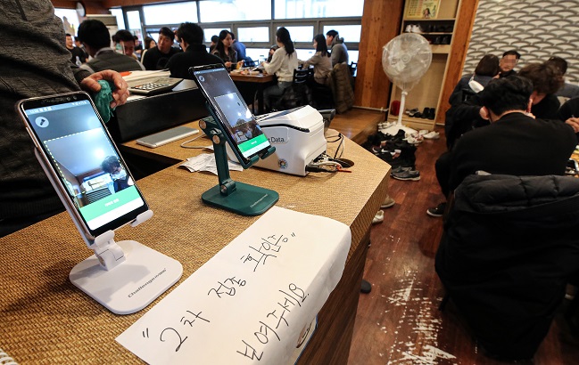 Mobile phones are installed at a restaurant in central Seoul on Dec. 13, 2021, to check visitors' COVID-19 vaccine pass through a quick-response (QR) code service. (Yonhap)