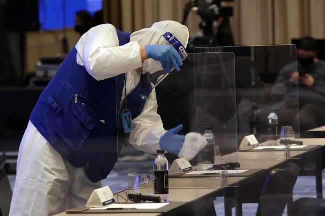 A quarantine official disinfects a protective cubicle barrier ahead of a conference at Four Seasons Hotel in Seoul on Dec. 16, 2021. (Yonhap)